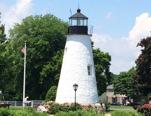 The Concord Point Lighthouse is a solid white lighthouse with a black point surrounded by bushes and benches. (Photo: Marcia Smith)