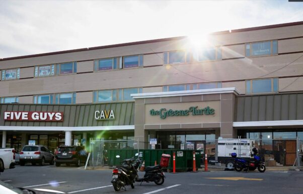 The outside of the new Green Turtle in College Park with fencing and a dumpster in front of it. To its left is a Cava and Five Guys. (Photo: Riley Sims/University of Maryland)