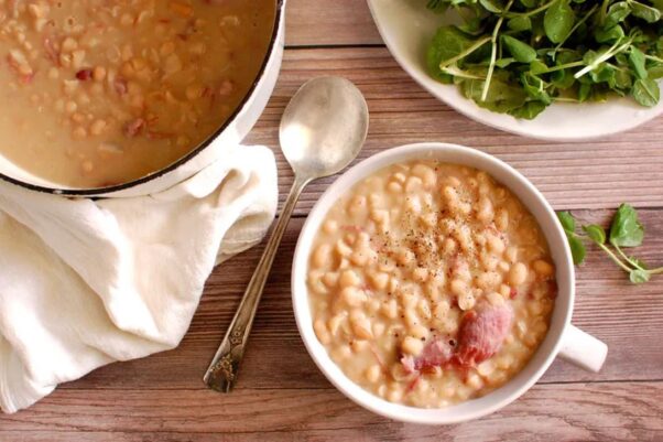 A white bowl filled with Senate Bean Soup on a table with the pot of soup, a salad and a spoon. (Photo: Contributed)
