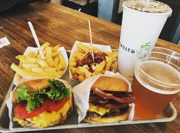 Two cheeseburgers in paper wrappers, two orders of fries, a soda and a beer sit on a silver tray. (Photo: Shake Shack/Facebook)