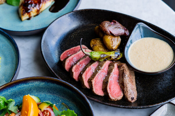 The Wren's new grilled angus beef tenderloin with smashed fingerling potatoes and wagyu demi espuma on a black plate. (Photo: Wren)