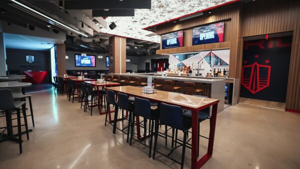 The wooden bar in District E with high top tables and chairs and TVs above the wood bar. (Photo: Monumental Sports)