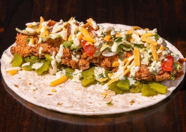 Torchy's Trailer Park taco with fried chicken, green chiles, lettuce, pico de gallo, mixed cheese and poblano sauce on a flour tortilla sitting on a wood table. (Photo: Torchy's Tacos)