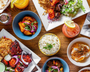 Dishes and plates with various kaboba, rice, salad and a drink on a wood table. (ZiZa Kabob/Facebook)