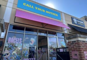 The exterior of Call Your Mother deli in Vienna with a blue sign & yellow letters and pink awning. (Photo: Angela Woolsey)