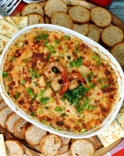 Hot, browned crab and shrimp dip with spinach in a white, ceramic baking dish with a few whole shrimps on top and bread and crackers around the dish. (Photo: Contributed)