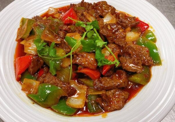 Stir-fried pepper steak sautéed with onions, green and red peppers in a white bowl. (Photo: Dolan Uyghur/Facebook)