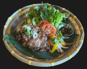 Eat a Lao's "Have Some Neck" with grilled marinated pork shoulder, cilantro, lettuce, scallion and spicy tamarind sauce on a black plate. (Photo: Eat a Lao)