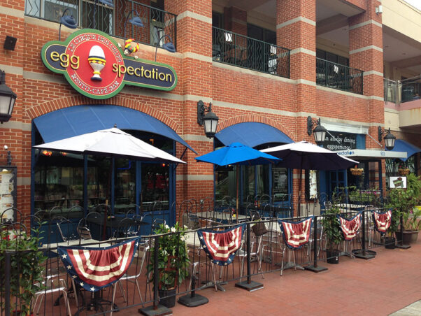 The exterior of the former Eggspectation in Downtown Silver Spring with a fenced patio with tables and umbrellas. (Photo: Pete Tan)