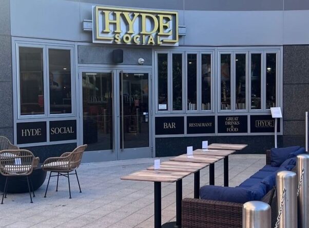 Exterior of Hyde Social with sign about the door and wood-topped tables, chairs and navy banquettes on the patio. (Photo: Hyde Social/Instagram)