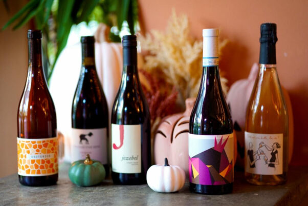 Five bottles of wine sitting on a counter with mini white and teal pumpkins. (Photo: Lulu's Winegarden)