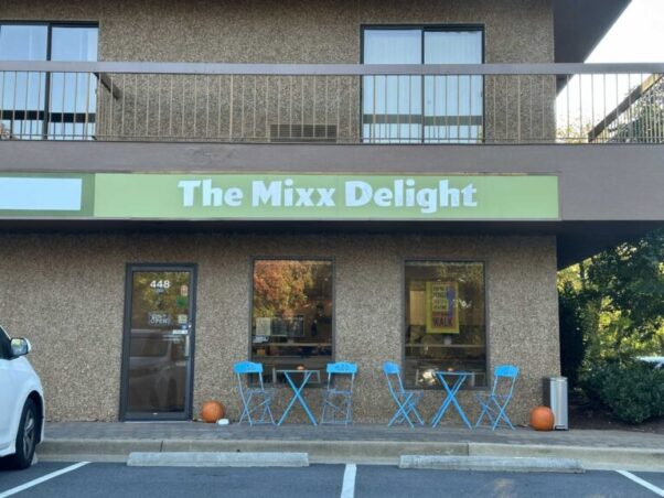 The exterior of The Mixx Delight with tables and chairs in front and a green sign with white letters across the front. (Photo: Anglea Woolsey)