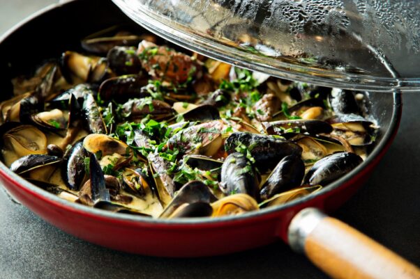 A red pan full of black mussels cooked in wine & lemon topped with parsley. (Photo: Mussel Bar/Facebook)