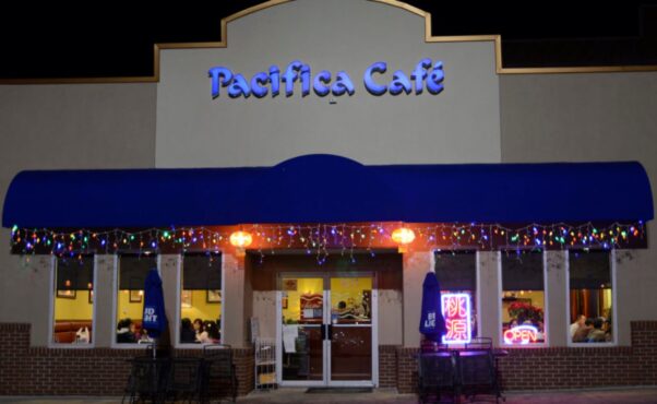 Exterior of Pacifica Cafe with a blue awning and multi-colored Christmas lights hanging from the awning. (Photo: Pacifica Cafe)