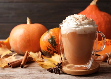 A pumpkin spice latte in a clear mug topped with whipped cream sits on a table with pumpkins and leaves. (Photo: Contributed)