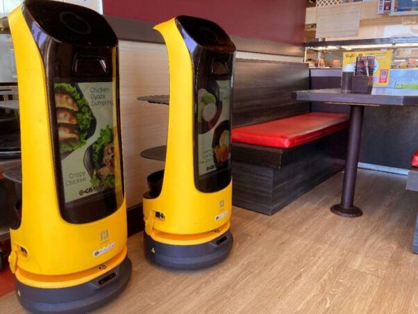 Two yellow Kur-Bs sit in the dining room beside an empty booth. (Photo; Kura Sushi)