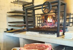 A wood-burning hearth with a fire in it and steaks waiting on a sheet pan. (Photo: Ruthie's All Day/Facebook)
