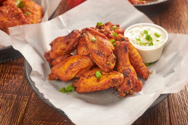 An order of smoked wings from Wood & Iron on white paper in a black plastic basket with a side of blue cheese dressing. (Photo: Wood & Iron/Facebook)
