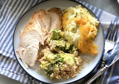 Broccoli and cheese casserole with Ritz crackers on a white plate with slices of turkey breast and cheesy scalloped potatoes. (Photo: Katie Jasiewicz)