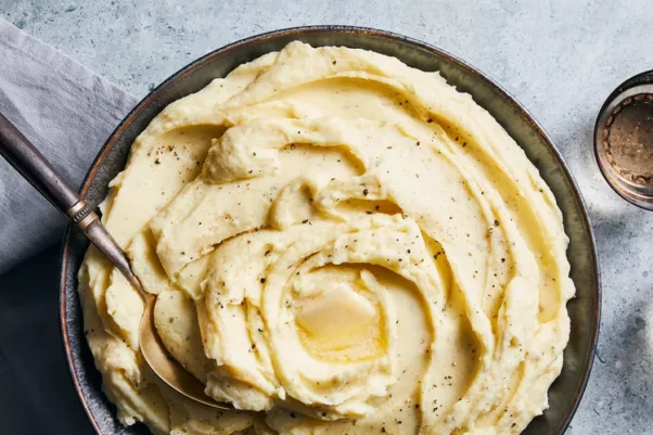 Garlic and herb mashed potatoes with melted butter on top in a black bowl. (Photo: Christopher Testani)
