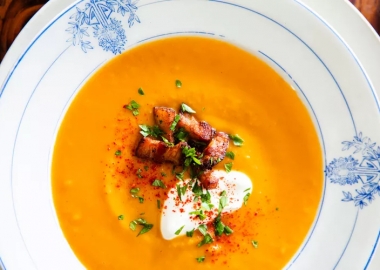 A bowl of butternut squash soup topped with creme fraiche, bacon, parsley and paprika. (Photo: Erin Kunkle)