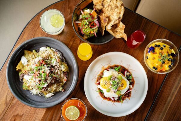 Four bowls filled with brunch food including eggs, cocktails and juices on a wood table. (Photo: dLeña)