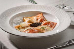 Three double-sided ravioli - one side white and one side red - in a shallow white bowl with caviar in the middle. (Photo: Marvin Torres)
