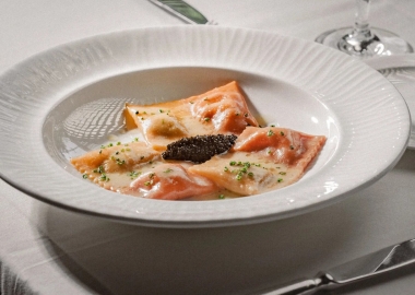 Three double-sided ravioli - one side white and one side red - in a shallow white bowl with caviar in the middle. (Photo: Marvin Torres)