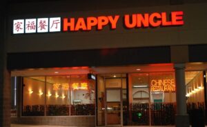 Exterior of Happy Uncle at night with sign lit and inside lights on. (Photo: Happy Uncle)