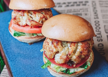 Two of Jimmy's Famous Seafood's crab cake sandwiches with tomato and lettuce on a blue plate. (Photo: Jimmy's Famous Seafood/Facebook)