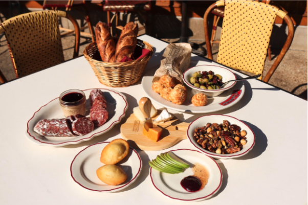 Items in Le Diplomat's home watch party snack pack in baskets & on plates on a table covered with a white table cloth. (Photo: Le Diplomat)