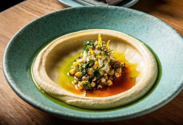 Albi's Maryland crab hummus with grilled corn, tatbili and green garlic in a light green bowl. (Photo: Albi/Instagram)