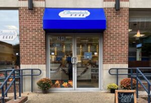 Exterior of Chewish Deli with bright blue awning. (Photo: Austin G./Yelp)