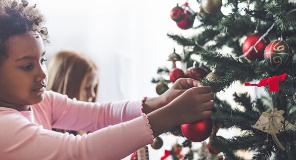 Black girl decorating a Christmas tree. (Photo: UPMC)