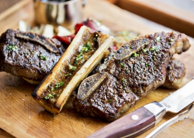 Beef short ribs with chimichurri sauce on a butcherblock with a steak knife beside it. (Photo: Scott Suchman)