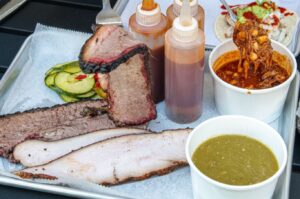 HiFi Tex-Mex BBQ's two meat combo with prime beef brisket and smoked turkey on a tray with pickles, a cup of smoked pork chile verde, a cup of Texas red chili and 3 bottles of BBQ sauce. (Photo: HiFi Tex-Mex BBQ/Instagram)
