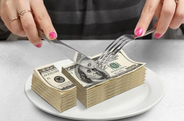 A diner cutting a pile of $100 bills with a knife and fork. (Photo: Getty Images)