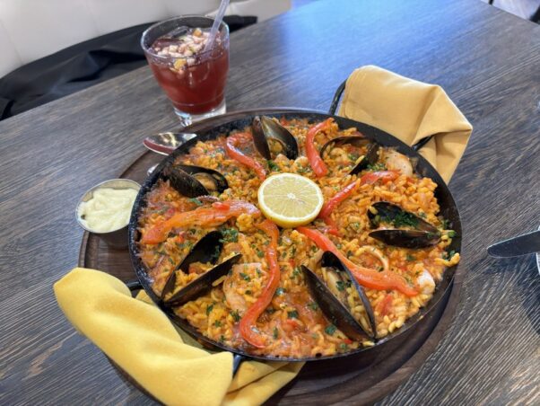 Paella de mariscos with bomba rice, safron, sofrito, stock, mussels, calamari, & shrimp in a paella pan on a wooden table. (Photo: Le C./Yelp)