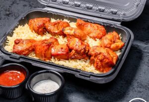 Zaytoun's chicken tikka over rice in a to-go container with sides of red sauce and white sauce. (Photo: Zaytoun)