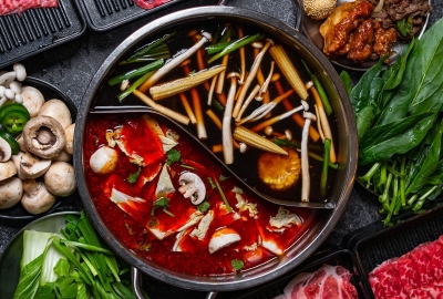 A divided hot pot with different broths and mushrooms in each side surrounded by raw meats and vegetables. (Photo: T Pot Hot Pot & Korean BBQ)